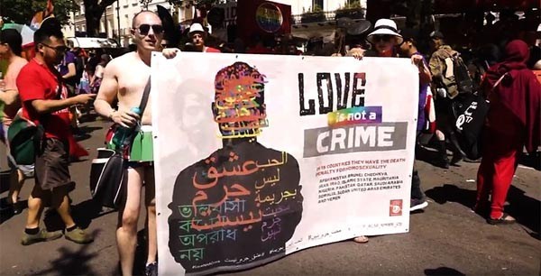 Pride photo of person holding banner saying love is not a crime